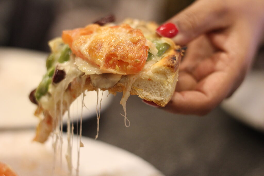 Crispy peel pizza grilled cheese sandwich with melted mozzarella oozing out, served on a wooden plate