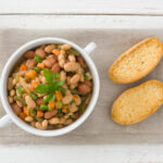 A close-up of a classic Southern beans and cornbread dish, featuring tender beans and golden cornbread slices served on a rustic plate.