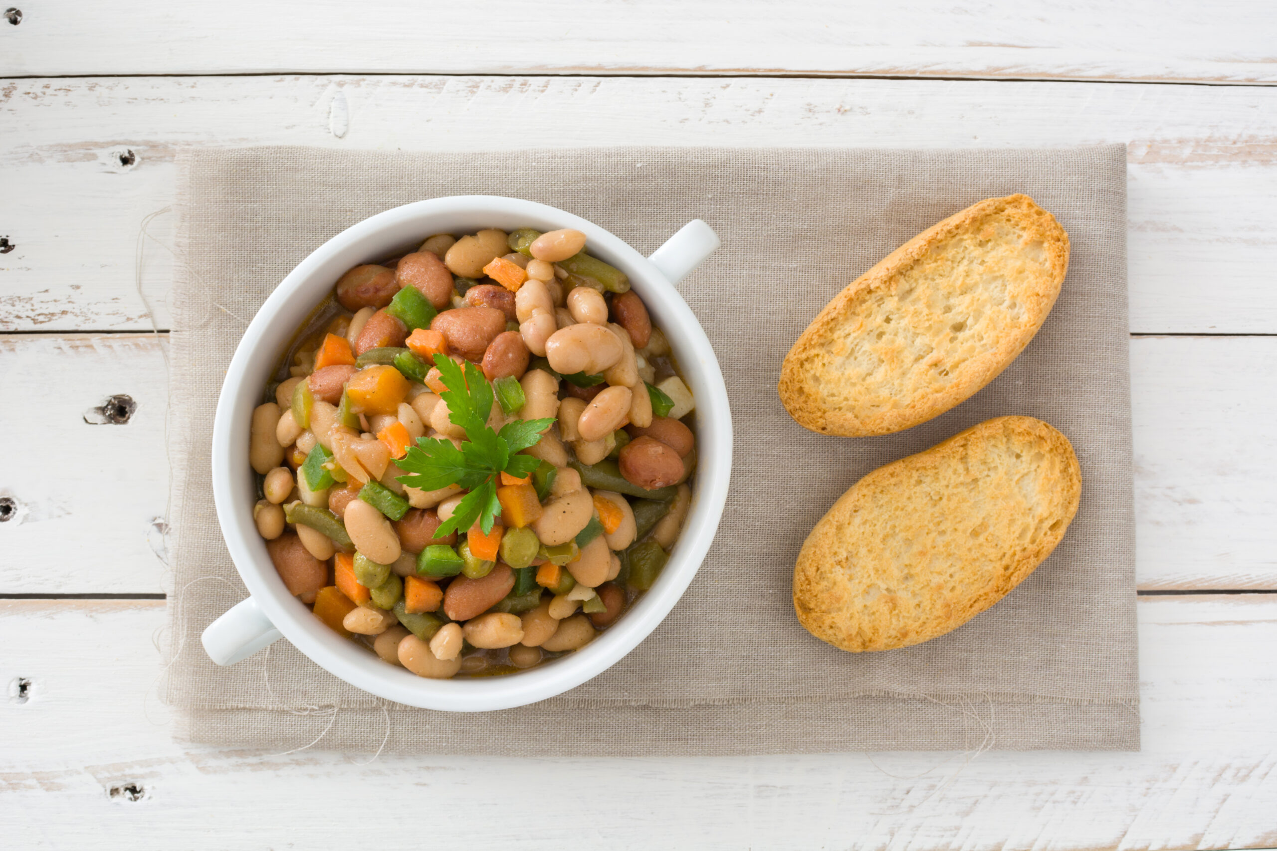 A close-up of a classic Southern beans and cornbread dish, featuring tender beans and golden cornbread slices served on a rustic plate.